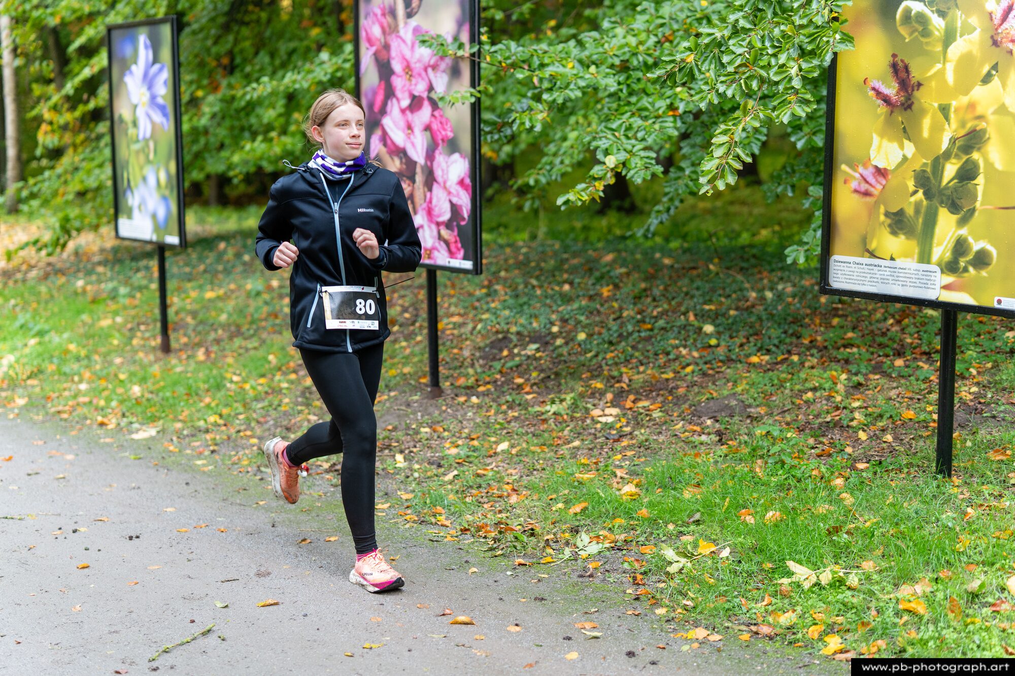 Biegaczka nadbiega aleją z tablicami kwiatów w Ogrodach Przelewice