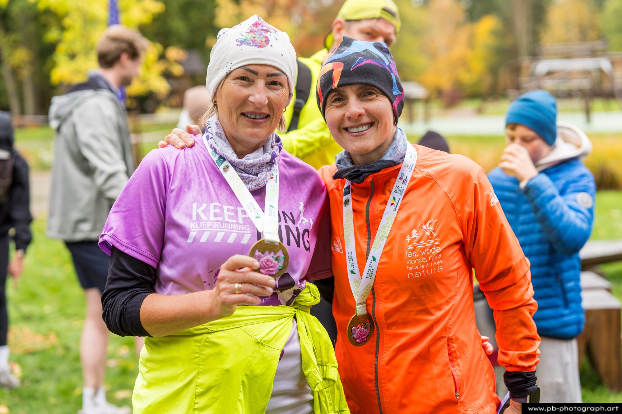 Dwie uczestniczki z medalami pozują do zdjęcia po biegu w deszczowy dzień